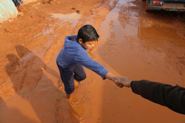 Person helping a child getting out of the mud